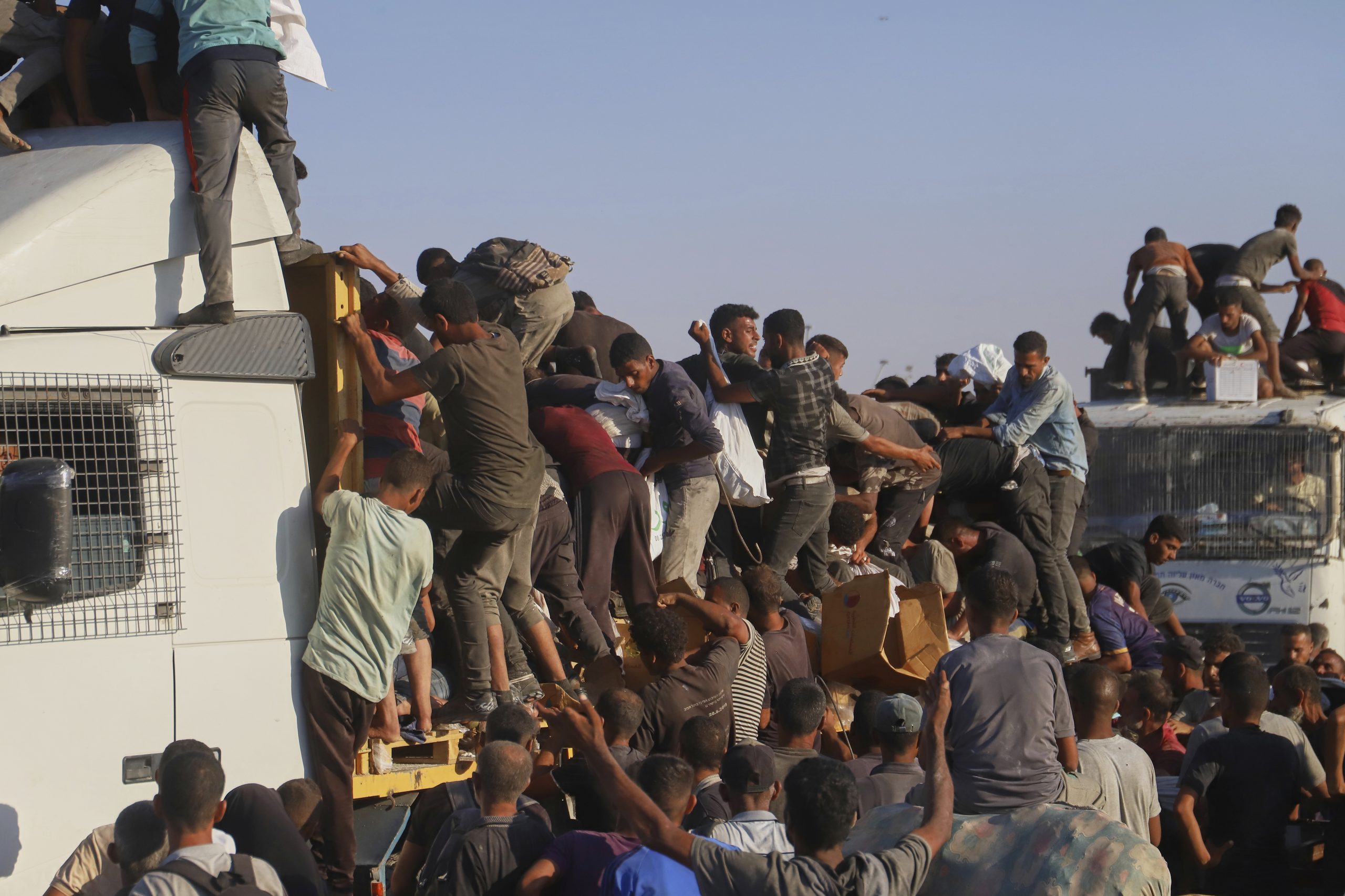 Palestinians struggle to get food and humanitarian aid from the back of a truck as it moves along the Morag corridor near Rafah, in the southern Gaza Strip, Monday, Aug. 4, 2025. (AP Photo/Mariam Dagga)